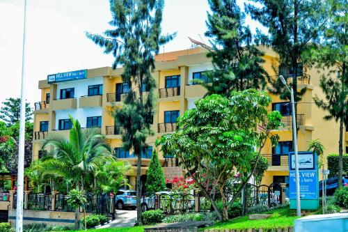 基加利Hill View Hotel Kiyovu的前面有树木的黄色建筑