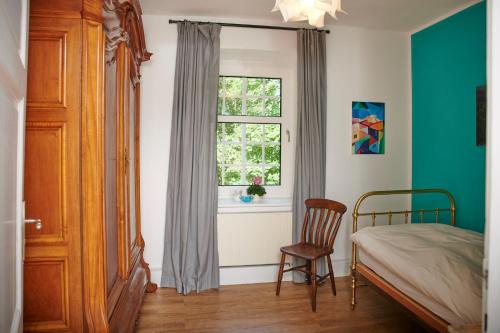 Charmantes Forsthaus beim Sorpesee的一间卧室配有一张床和一个带椅子的窗户