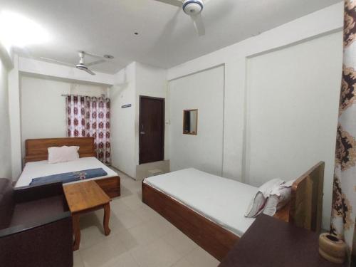 达卡New Hotel Labbaik的一间卧室配有两张床和一张桌子