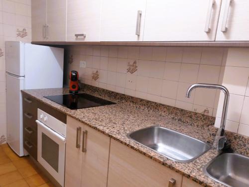 坎布里尔斯Rentalmar Sol de España - Mas d'en Gran的厨房柜台设有水槽和冰箱