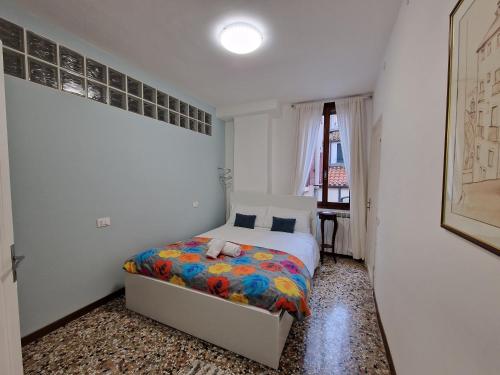 威尼斯Veneziacentopercento Apartments & Rooms的一间卧室配有一张带彩色毯子的床