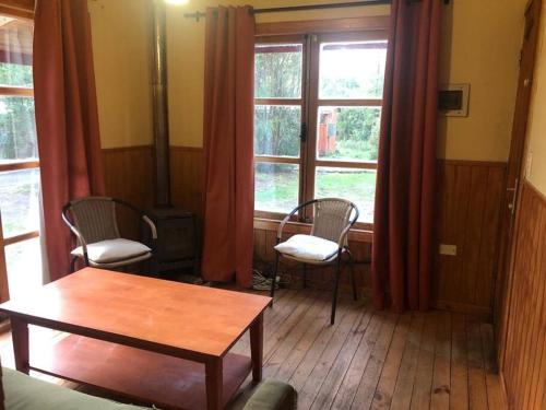 巴拉斯港Cabaña Haywood的客厅配有两把椅子和一张桌子,窗户
