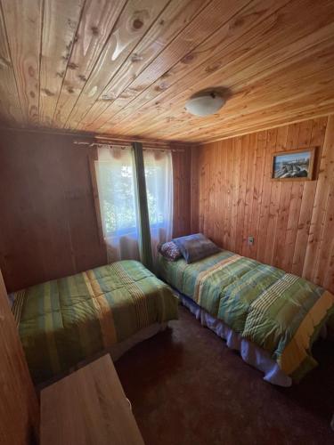普孔Cabaña Ojo del Volcán的木墙客房的两张床