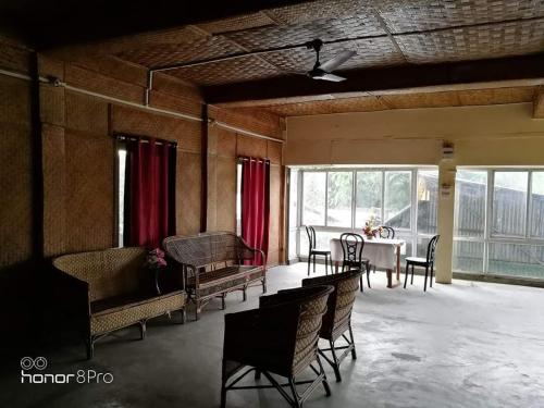 焦尔哈德Ashrayaa Prakreeti.的一间带桌椅的房间和一间用餐室