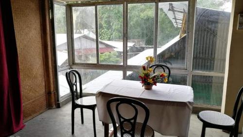 焦尔哈德Ashrayaa Prakreeti.的配有大窗户的客房内的桌椅