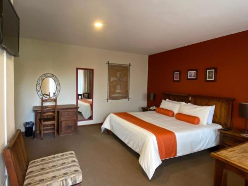 乔卢拉Capital O La Huerta Golf & Hotel的一间卧室配有一张大床和镜子