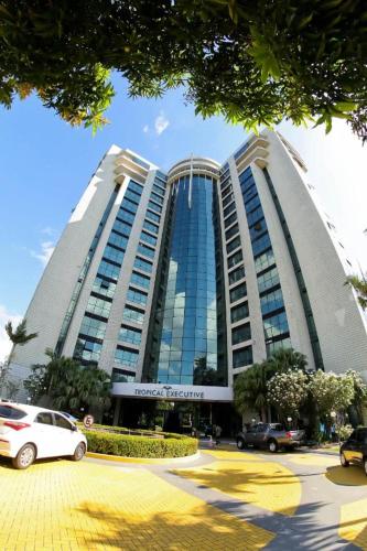 马瑙斯Tropical Executive Hotel的一座大型建筑,前面有汽车停放