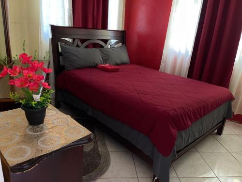 蒙特哥贝Elite's Ocean View的红色的床,红色的被子和花桌