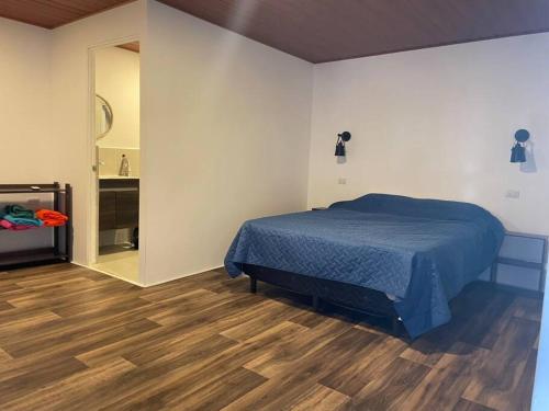 AcajutlaOcean fronthouse in Salinitas的一间卧室设有蓝色的床,铺有木地板。
