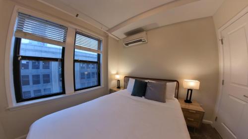 底特律Prime City Center Location! 2BR Near Everything!的卧室配有白色的床和2扇窗户。