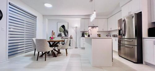 巴里Brand New! Modern Luxury Retreat!的厨房配有桌子和不锈钢冰箱。