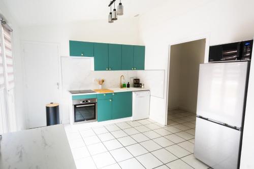 圣佩赖Charmant appartement au cœur de Saint-peray的厨房配有绿色橱柜和白色瓷砖地板。