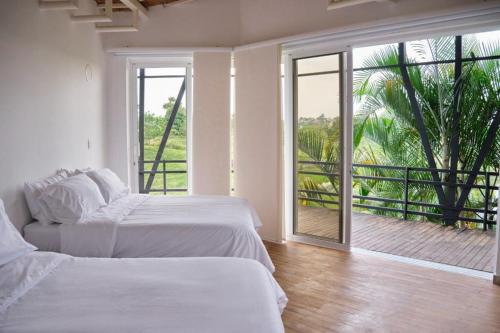 佩雷拉Hotel Casa Natura的带阳台的白色客房中的两张床