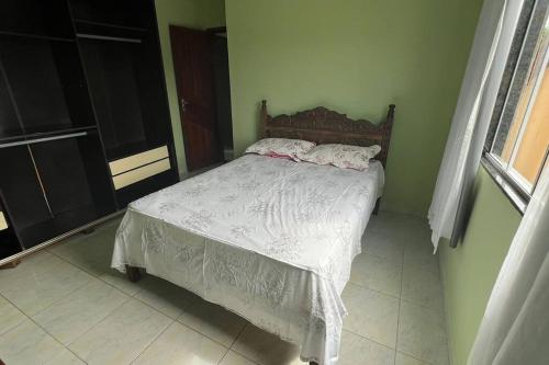 瓜拉派瑞Apartamento em Setiba的一间卧室配有一张带白色床单的床和一扇窗户。