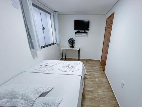 Lebrinhos hotel的白色的客房配有床和电视。