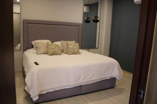 洛斯莫奇斯Departamento entero de lujo的卧室配有带金色枕头的大型白色床
