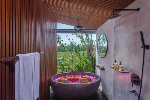 乌布IPIAN Angel by Pramana Villas的浴室配有鲜花盛开的大浴缸