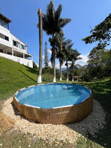 拉维加ALOJAMIENTO CAMPESTRE EN LA VEGA - A 1 HORA EXACTA DE BOGOTÁ的棕榈树庭院中的游泳池