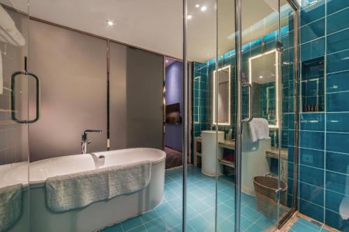 深圳南香楼艺术酒店(华侨城甘坑古镇店)的浴室设有浴缸和蓝色瓷砖淋浴。