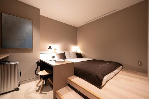 东京CAFE/MINIMAL HOTEL OUR OUR的一间卧室配有一张床、一张桌子和一张四柱床。