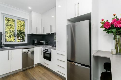 悉尼Studio Apartment in the heart of Newtown NMORE的厨房配有白色橱柜和不锈钢冰箱