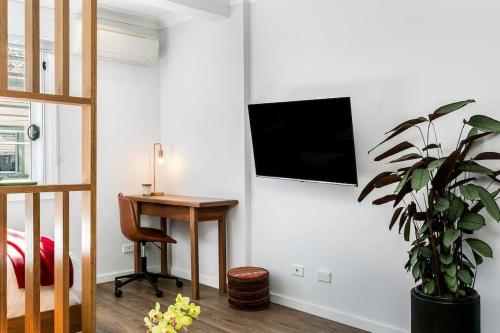 悉尼Studio Apartment in the heart of Newtown NMORE的一间卧室配有书桌,墙上配有电视