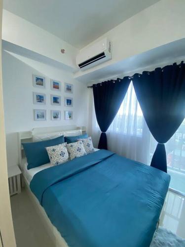 马尼拉Serene Skyline Escape Las Pinas的卧室内的一张蓝色的床,卧室设有窗户