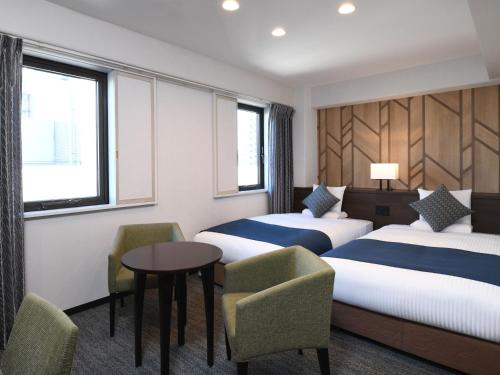 厚木HOTEL MYSTAYS Atsugi的酒店客房带两张床和一张桌子以及椅子。