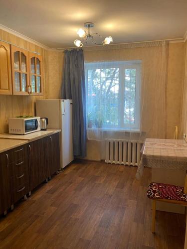 卡拉甘达Тихая теплая уютная однушка的厨房配有冰箱、桌子和窗户。