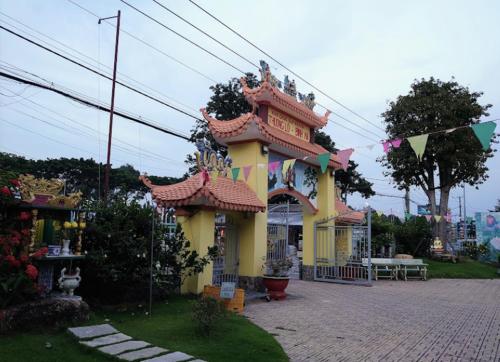 巴地市Ruby Motel Bà Rịa的前面有旗帜的小黄色建筑