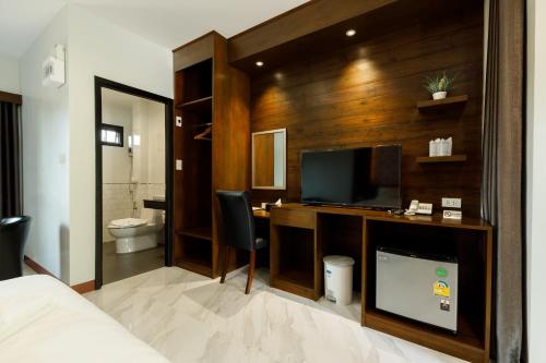 洛坤府บีวินรีสอร์ท的一间卧室设有一张桌子、一台电视和一间浴室。
