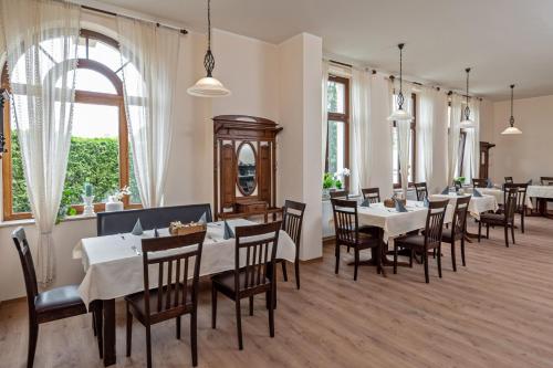 海德瑙芮彻斯科奈酒店的餐厅设有白色的桌椅和窗户。