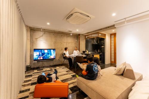 镰仓市Tre casa hotel KAMAKURA的一群坐在客厅看电视的孩子