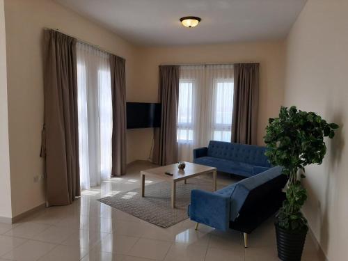 拉斯阿尔卡麦Hala Holiday Homes- Bab Al Bahr Residence, Al Marjan Island的客厅配有蓝色的沙发和桌子