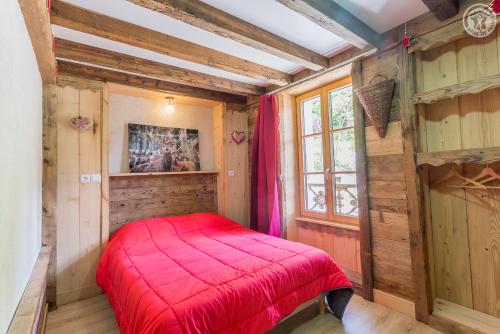 泰尔米尼翁LA DENT PARRACHEE的一间设有红色床的卧室,位于一个木墙的房间