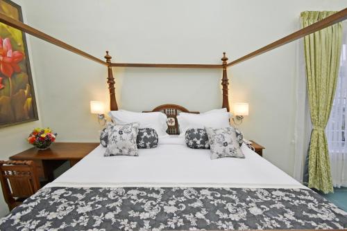 蓬蒂切里Le Colonial Suites的卧室配有带枕头的大型白色床