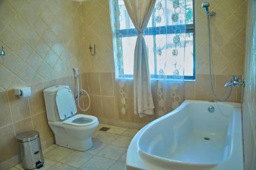 卡拉图MACHAGE TOURS AND SAFARIS HOTEL的一间带卫生间和浴缸的浴室以及窗户。