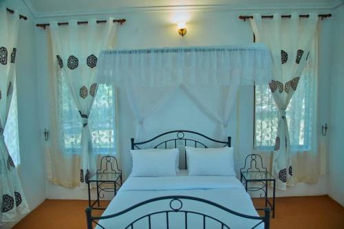 卡拉图MACHAGE TOURS AND SAFARIS HOTEL的一间卧室配有蓝色的床和白色窗帘