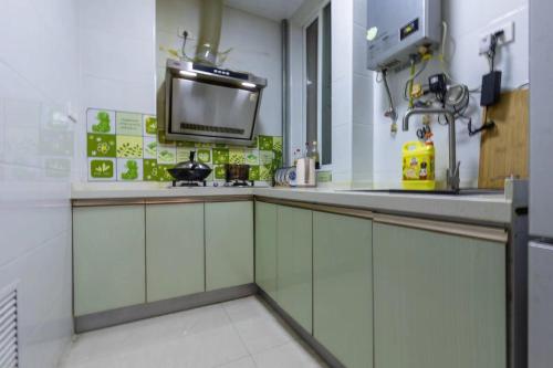 淮南淮南东城国际两居室公寓的一间厨房,配有白色橱柜和墙上的电视