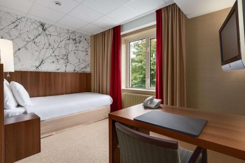 费尔德霍芬康宁小夫NH埃因霍温会议中心酒店的酒店客房配有一张床、一张书桌和电话