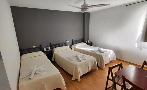 比亚雷亚尔Hello Villarreal Pension的客房设有三张床、白色床单和桌子