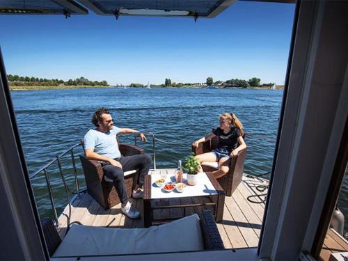 金洛伊Attractive houseboat in Kinrooi with terrace的两个人坐在水面上的船上