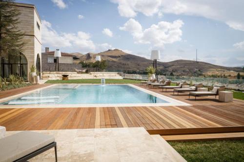 于尔居普Villa Boutique Cappadocia的一座带椅子的庭院和一座建筑中的游泳池