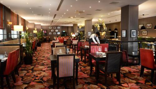 都柏林都柏林阿什林酒店的配有桌椅的餐厅,在柜台工作的男人