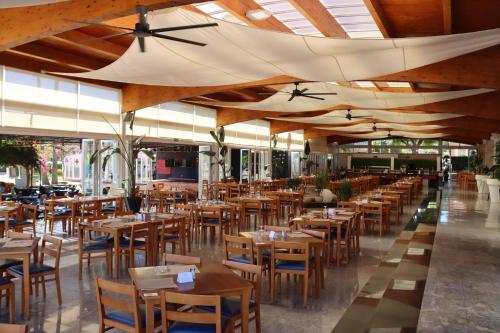 卡拉米洛Aparthotel Ciudad Laurel的餐厅设有木桌、椅子和天花板。