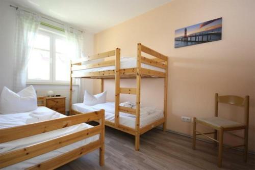 奥斯赛拜-屈隆斯博恩Strandschloesschen-Haus-II-WE-18-9723的一间卧室配有两张双层床和椅子