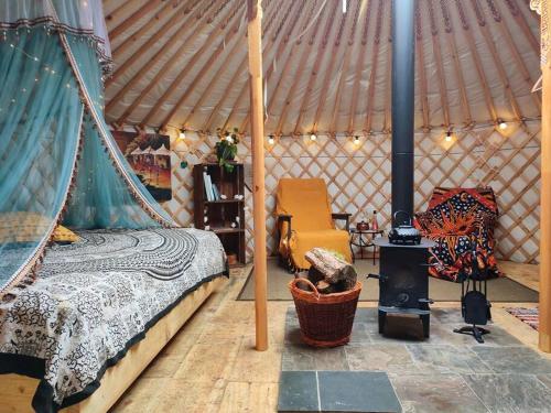 多尔盖罗Pandy Farm Yurt - Panoramic mountain views within Snowdonia's National Park - 4x4 recommended的蒙古包内一间卧室配有一张床和一个炉灶