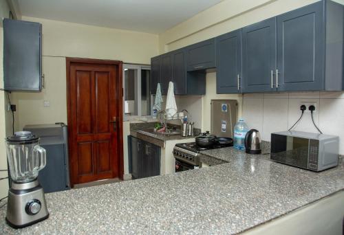 坎帕拉FG Homestay, Kampala Muyenga-Bukasa的厨房配有蓝色橱柜和台面