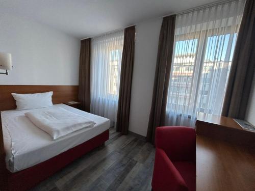 纽伦堡法克曼酒店的一间卧室配有一张床、一把椅子和窗户。