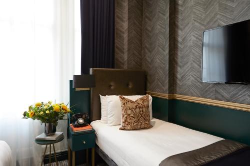 伦敦The Portico Hotel的卧室配有一张床铺,墙上配有电视